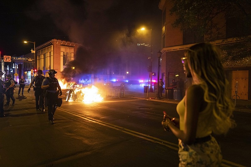 Police stand guard after protesters set fire to dumpsters on the street after a vigil was held for Winston Boogie Smith Jr. early on Saturday, June 5, 2021. Smith was shot and killed by law enforcement officers on Thursday during an arrest warrant operation. (AP Photo/Christian Monterrosa)


