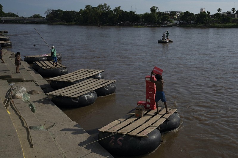 Photo by Moises Castillo of The Associated Press / Rafts carry passengers and supplies across the Suchiate River between Tecun Uman, Guatemala, left, and Ciudad Hidalgo, Mexico, on, June 5, 2021.