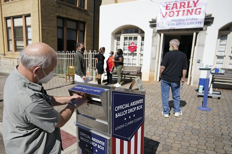 FILE - In this Monday, Oct. 19, 2020 file photo, a voter submits a ballot in an official drop box during early voting in Athens, Ga. (AP Photo/John Bazemore, File)


