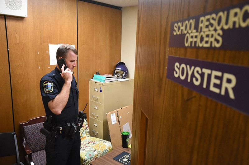 Hamilton County Sheriff's Deputy P. Soyster, school resource officer for Central High School, talks on the phone in his school office in Harrison.