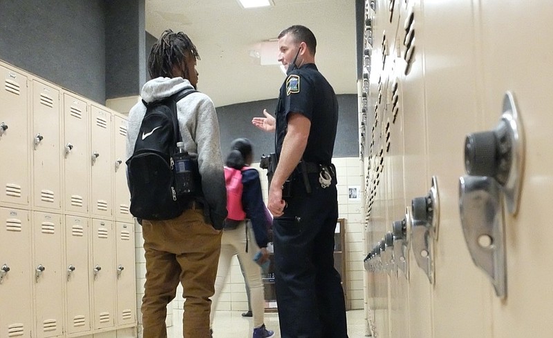 Staff photo by Tim Barber / School Resource Officer P. Soyster, right, talks with 12th grade senior Michael Wright in the hallway following the final lunch period Wednesday at Central High School in Harrison.