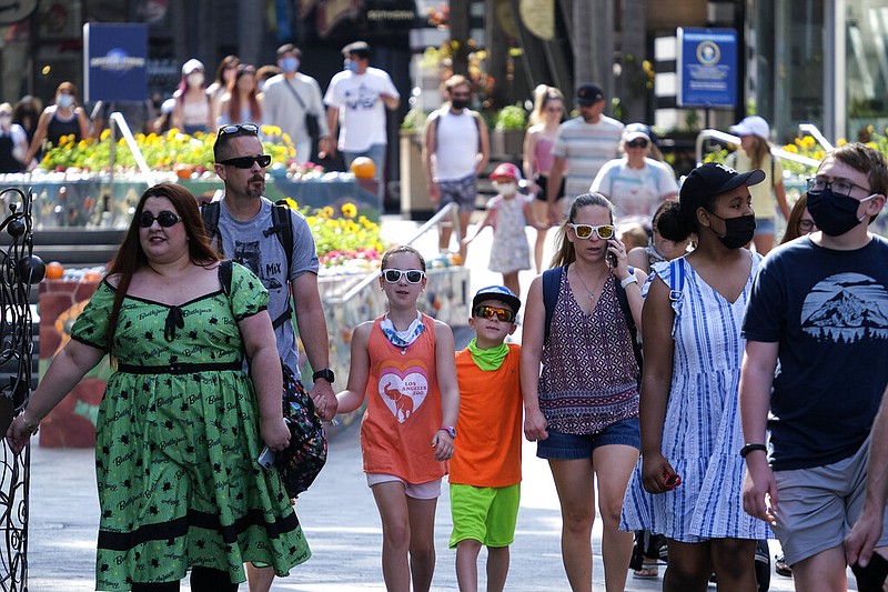 In this June 15, 2021, file photo, people arrive at Universal Studios in Universal City, Calif. Many Americans are relaxing precautions taken during the COVID-19 pandemic and resuming everyday activities, even as some worry that coronavirus-related restrictions were hastily lifted, according to a new poll from The Associated Press-NORC Center for Public Affairs Research. (AP Photo/Ringo H.W. Chiu, File)