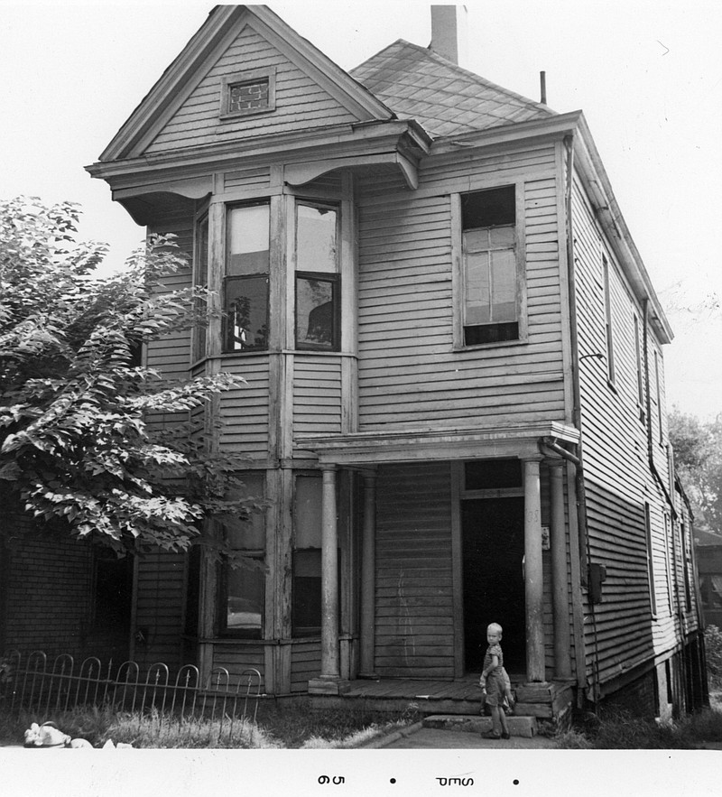 A small child stands in front of a towering two-story house on the west side in 1955. Photo by Pat St. Charles, Jr., contributed by ChattanoogaHistory.com.