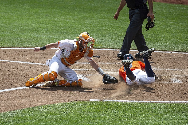 AP photo by John Peterson / Virginia's Alex Tappen slides into home plate to score past Tennessee catcher Connor Pavolony in the seventh inning of their College World Series matchup Sunday in Omaha, Neb.