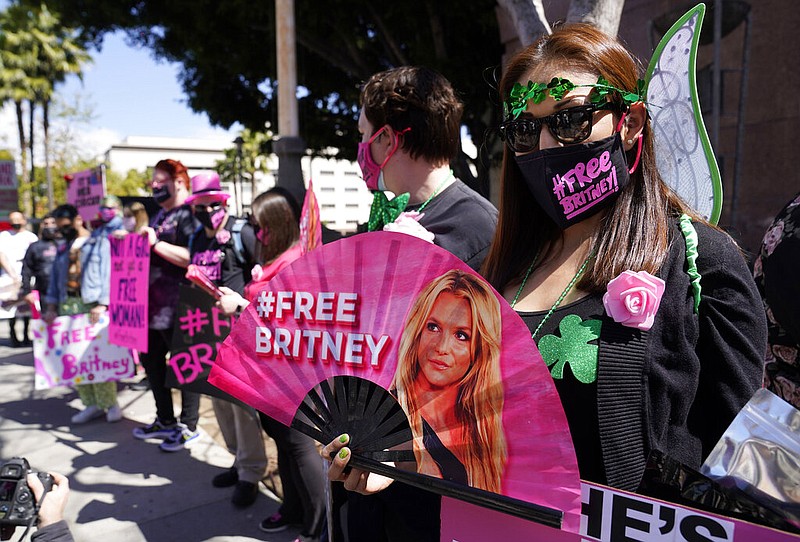 Britney Spears supporter Kiki Norberto holds a hand fan outside a court hearing concerning the pop singer's conservatorship on March 17, 2021, in Los Angeles. When Spears speaks to a judge at her own request on Wednesday, June. 23, 2021, she'll do it 13 years into a court-enforced conservatorship that has exercised vast control of her life and money by her father. Spears has said the conservatorship saved her from collapse and exploitation. But she has sought more control over how it operates, and says she wants her father out. (AP Photo/Chris Pizzello, File)
