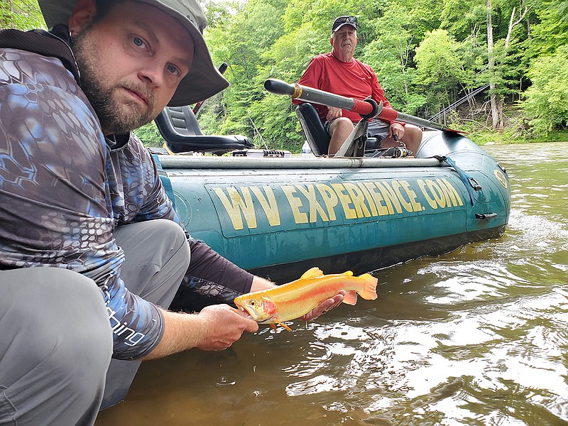 Photo contributed by Larry Case / Fishing guide Adam Hedrick of the West Virginia Experience, left, displays a golden trout as Dave Young looks on from the raft in the Gauley River.