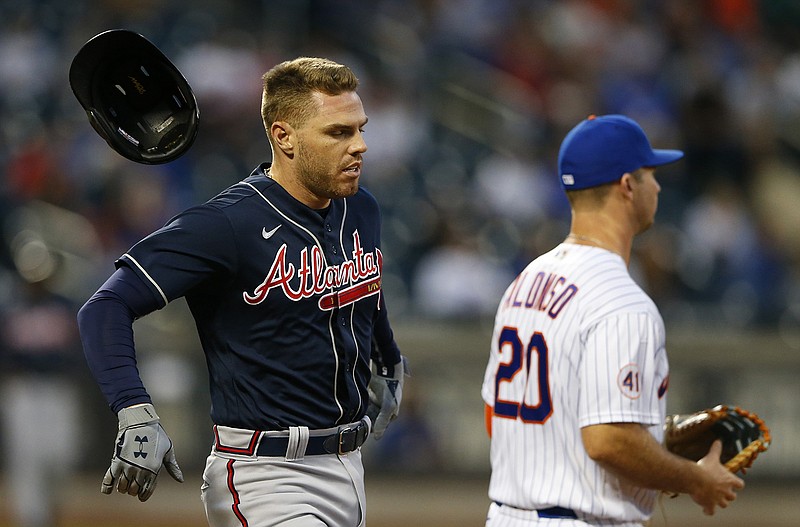 AP photo by Noah K. Murray / The Atlanta Braves' Freddie Freeman, left, loses his helmet running to first base during the fourth inning of Wednesday's game against the host New York Mets.