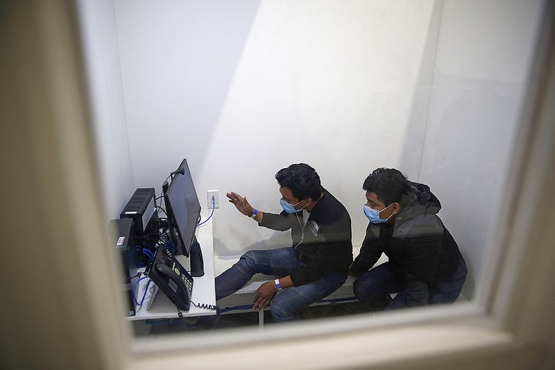 Associated Press File Photo / Unaccompanied migrant children speak to their relatives inside a phone booth after being processed at the intake area of the U.S. Customs and Border Protection facility in Donna, Texas, in March.