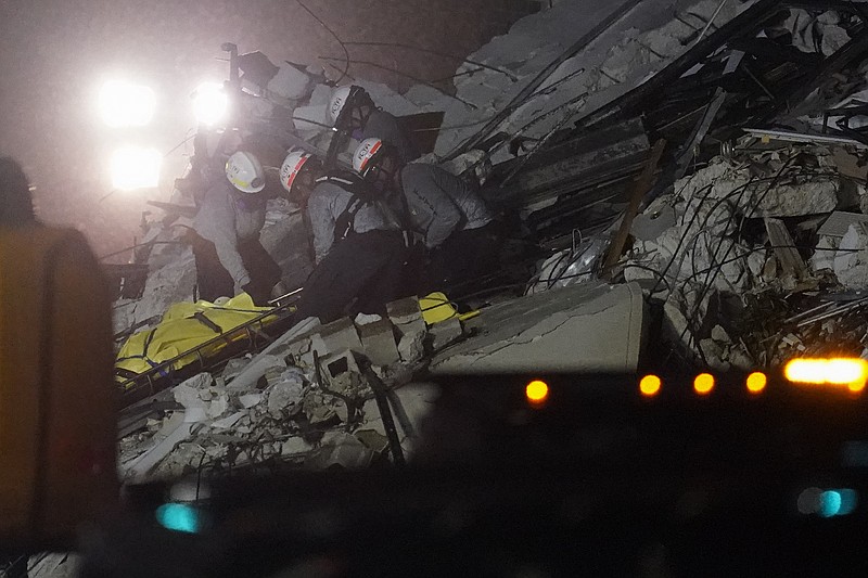 Rescue workers remove a body from the rubble where a wing of a 12-story beachfront condo building collapsed, Thursday, June 24, 2021, in the Surfside area of Miami.(AP Photo/Gerald Herbert)