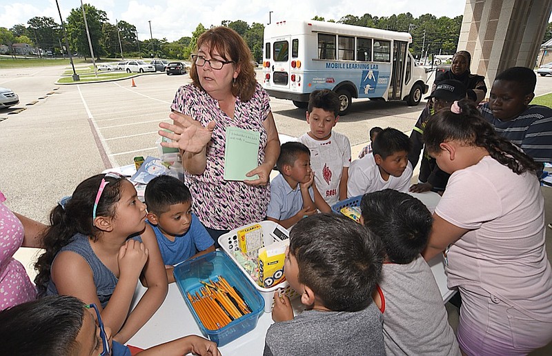 Staff Photo by Matt Hamilton / Teacher Rita Schubert leads a group of students in a project as part of a mobile learning center outside East Ridge Elementary School Wednesday, June 30, 2021.
