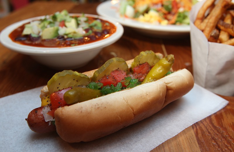 Staff file photo by Patrick Harding / GOOD DOG, on Frazier Ave., offers a variety of different style dogs and other fare, such as freshly cut fries and home stewed chili and salads. Pictured is the Chicago Dog, complete with neon green relish, sport peppers and celery salt with a bowl of House "Fav" chili, large frite and dog house salad.