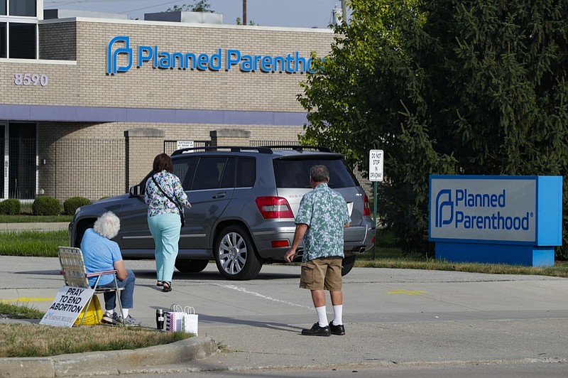 FILE - In this Aug. 16, 2019 file photo, abortion protesters attempt to handout literature as they stand in the driveway of a Planned Parenthood clinic in Indianapolis. (AP Photo/Michael Conroy)


