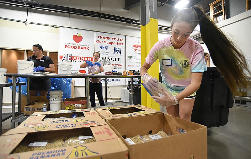 Staff Photo by Matt Hamilton / Sterling Tittsworth, 17, places bagged pasta in boxes at the Chattanooga Area Food Bank on Tuesday, July 6, 2021. 