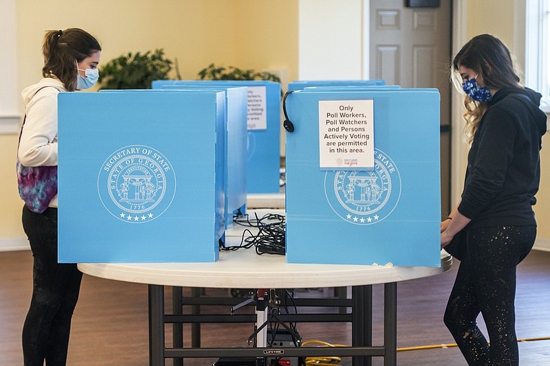 FILE - In this Jan. 5, 2021, file photo, Emily Murdock, left, and her twin sister Elizabeth Murdock vote in Georgia's U.S. Senate runoff election in Evans, Ga. A federal judge on Wednesday, July 7, 2021, declined to block some challenged sections of Georgia's new election law ahead of two runoff elections scheduled for next week, but he didn't rule out the possibility for future elections. (Michael Holahan/The Augusta Chronicle via AP)