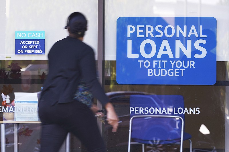 In this Oct. 1, 2020 file photo, a woman walks past a personal finance loan office in Franklin, Tenn. There is no federal maximum interest rate on consumer loans, so absent a state law, lenders can charge high rates on small loans . But recently, more states have moved to bring that number down. (AP Photo/Mark Humphrey, File)