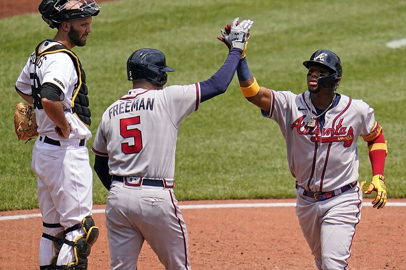 Atlanta Braves' Ronald Acuna Jr., right, celebrates with Freddie Freeman (5) as Pittsburgh Pirates catcher Jacob Stallings, left, looks on, after hitting a solo home run off starting pitcher Wil Crowe during the third inning of a baseball game in Pittsburgh, Wednesday, July 7, 2021. (AP Photo/Gene J. Puskar)