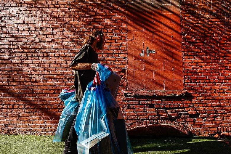 Staff photo by Troy Stolt / Mitchell Crist carries bags of litter to give to the Cash for Trash program set up by the The Downtown Chattanooga Alliance on Thursday, July 15, 2021 in Chattanooga, Tenn. The program offers Chattanooga's homeless population four dollars a bag for up to five bags of litter a day, four days a week in the form of payment cards to select downtown businesses.