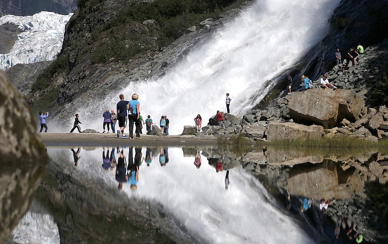 In this July 31, 2013, file photo, tourists visiting the Mendenhall Glacier in the Tongass National Forest are reflected in a pool of water as they make their way to Nugget Falls in Juneau, Alaska. The Biden administration said Thursday, July 15, 2021, that it is ending large-scale, old-growth timber sales on the nation's largest national forest, the Tongass National Forest in Alaska, and will instead focus on forest restoration, recreation and other non-commercial uses. (AP Photo/Charles Rex Arbogast, File)