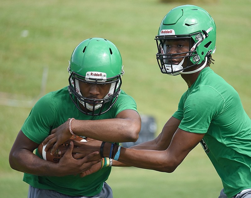 Staff file photo / East Hamilton quarterback Jeremiah Flemmons hands the ball off to running back Juandrick Bullard during a recent practice. The Hurricanes tandem ranks as one of the area's best offensive backfields heading into the season.