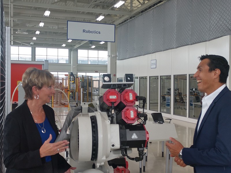 Staff photo by Mike Pare / Mary Beth Hudson, left, director of the Smart Factory Institute in Chattanooga, talks with Mario Duarte, director of human resources for Volkswagen in the city, next to a welding robot at the Volkswagen Academy.