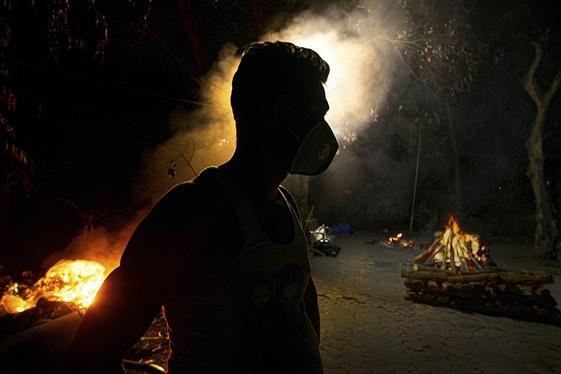 FILE - In this Sept. 14, 2020, file photo, Ramananda Sarkar, 43, who has cremated more than 450 COVID-19 victims stands by burning funeral pyres of COVID-19 victims in Gauhati, India. India's excess deaths during the pandemic could be a staggering 10 times the official COVID-19 toll, likely making it modern India's worst human tragedy, according to the most comprehensive research yet on the ravages of the virus in the south Asian country. (AP Photo/Anupam Nath, File)