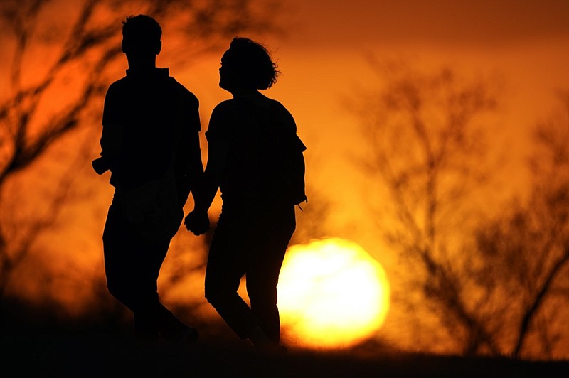 FILE - In this Wednesday, March 10, 2021 file photo, a couple walks through a park at sunset in Kansas City, Mo. (AP Photo/Charlie Riedel, File)



