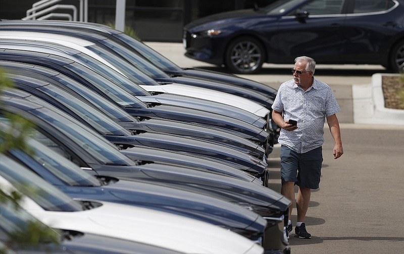 In this Sunday, June 14, 2020, photograph, a prospective buyer looks over a long row of unsold 2020 CX-5 sports-utility vehicles sedans sits at a Mazda dealership in Littleton, Colo. With car prices at record highs and inventory getting thinner, shoppers might be tempted to rush through a deal this summer without giving it much thought. (AP Photo/David Zalubowski)
