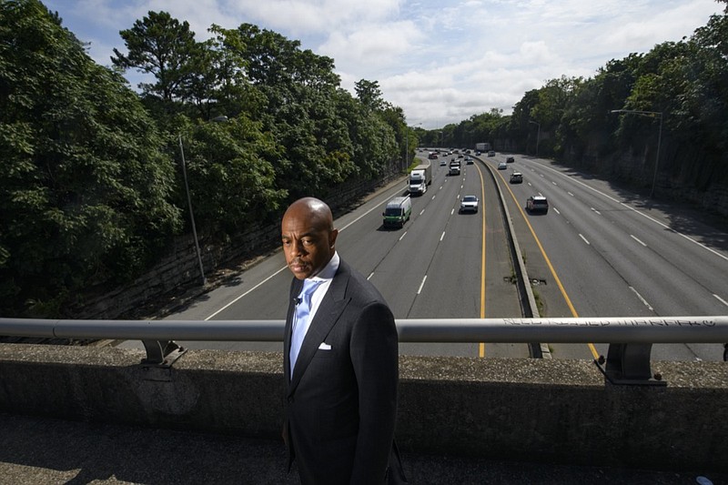 Tennessee State Rep. Harold Love, Jr. stands on an overpass over I-40, Monday, July, 19, 2021, near the site of his family's former home on the north side of Nashville, Tenn. Love Jr.'s father, a Nashville city councilman, was forced to sell his home near here to make way for the highway, but put up a fight in the 1960s against the rerouting of Interstate 40 because he believed it would stifle and isolate Nashville's Black community. Love Jr. is now part of a group pushing to build a cap across the highway, behind him, that creates a community space to help reunify the city. (AP Photo/John Amis)