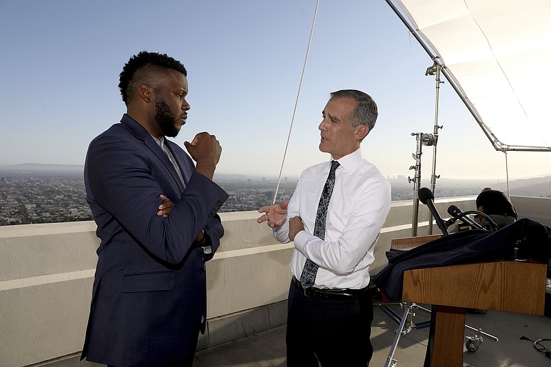 FILE - In this April 19, 2021 file photo, Los Angeles Mayor Eric Garcetti, right, talks with Michael Tubbs, founder of Mayors for a Guaranteed Income, after holding his annual State of the City address from the Griffith Observatory, in Los Angeles. In experiments across the country, dozens of cities and counties, some using money from the $1.9 trillion COVID relief package approved in March, and the state of California are giving some low-income residents a guaranteed income of $500 to $1,000 each month to do with as they please, and tracking what happens. (Gary Coronado/Los Angeles Times via AP, Pool File)