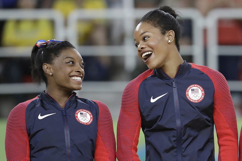  U.S. gymnasts and gold medallists, Simone Biles, left and Gabrielle Douglas celebrate on the podium during the medal ceremony for the artistic gymnastics women's team at the 2016 Summer Olympics in Rio de Janeiro, Brazil.