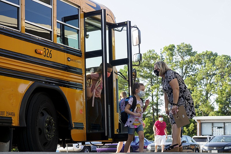 Staff photo by C.B. Schmelter / Assistant Principal Jennifer Rodgers, right, helps students exit a bus on the first day of school at Hixson Elementary School on Wednesday, Aug. 12, 2020, in Hixson.