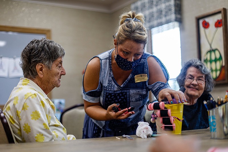 Staff photo by Troy Stolt / Juanita Brooks, Program Director at The Lantern at Morning Pointe Alzheimer's Center of Excellence, center, asks resident Diane Scanlan, left, what color she would like her nails painted as resident on Shirley Sklar, right, on Wednesday, July 28, 2021 in East Brainerd, Tenn. The Lantern is reopening a little over a year after the tornado damaged the facility.
