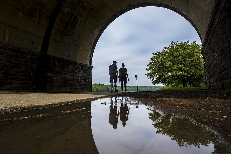 FILE - In this May 14, 2018 file photo, a couple walks on a path at Fairmount Park as they proceed under the trestle bridge over the Schuylkill River in Philadelphia. Tending your garden also offers lessons for growing your money. Start by defining what you want to bring to life. Think about the various aspects of your finances — income, expenses, debts — and imagine what you want them to look like in one or five years' time. (Michael Bryant/The Philadelphia Inquirer via AP)