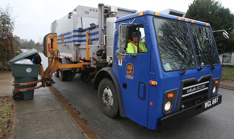 Staff Photo by D. Patrick Harding Ben Cox, a Chattanooga City garbage truck driver and operator, controls a mechanical arm as it picks up a trash can. The city of Chattanooga will temporarily suspend its recycling service after Friday, July 30, 2021, due to a driver shortage.