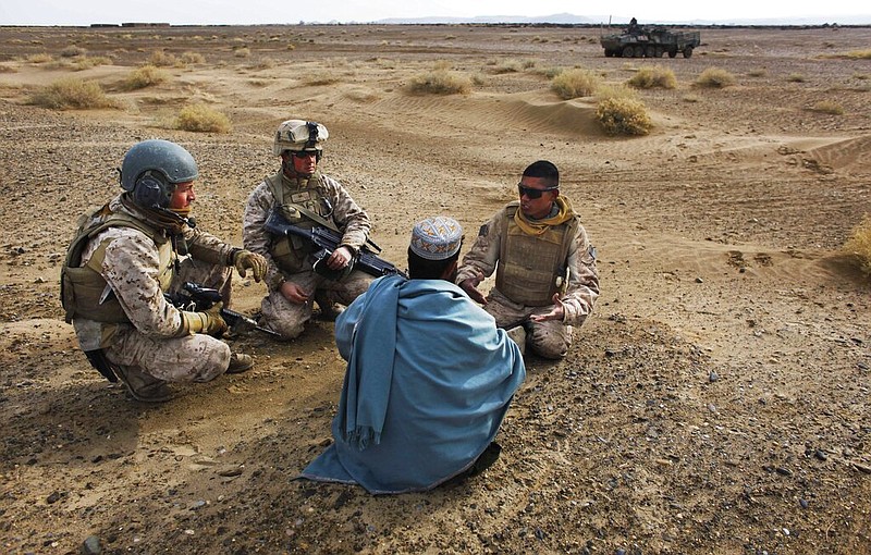 In this Friday, Dec. 11, 2009, file photo, United States Marine Sgt. Isaac Tate, left, and Cpl. Aleksander Aleksandrov, center, interview a local Afghan man with the help of a translator from the 2nd MEB, 4th Light Armored Reconnaissance Battalion on a patrol in the volatile Helmand province of southern Afghanistan. More than 200 Afghans were due to land Friday in the United States in the first of several planned evacuation flights for former translators and others as the U.S. ends its nearly 20-year war in Afghanistan. (AP Photo/Kevin Frayer, File)
