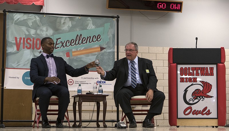 Staff photo by C.B. Schmelter / District 9 challenger D'Andre Anderson, left, hands the microphone to incumbent Steve Highlander during a school board debate hosted by UnifiEd and Chattanooga 2.0 at Ooltewah High School on Monday, May 14, 2018 in Ooltewah, Tenn.