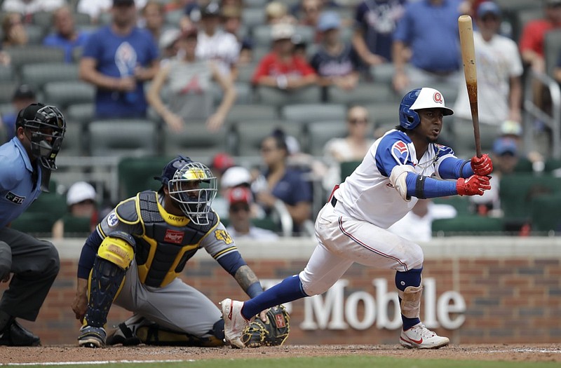 Atlanta Braves' Ozzie Albies, right, grounds out in the seventh inning of a baseball game against the Milwaukee Brewers Sunday, Aug. 1, 2021, in Atlanta. (AP Photo/Ben Margot)