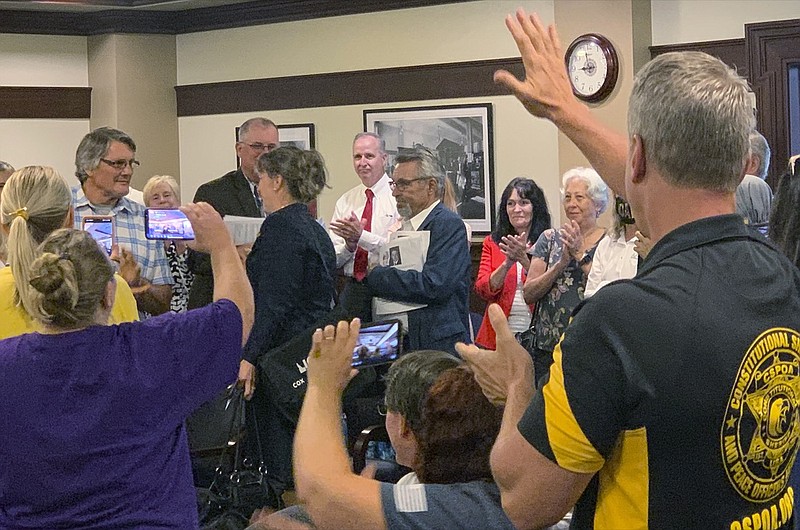 Republican Rep. Priscilla Giddings, left center in black, enters her ethics committee hearing Monday, Aug. 2, 2021, to applause and shouts of encouragement from supporters in the audience in Boise, Idaho. An Idaho lawmaker accused of violating ethics rules by publicizing the name of an alleged rape victim in disparaging social media posts, and then allegedly misleading lawmakers about her actions, said in an ethics hearing Monday that she did nothing wrong and claimed the allegations against her were politically motivated. (AP Photo/Rebecca Boone)