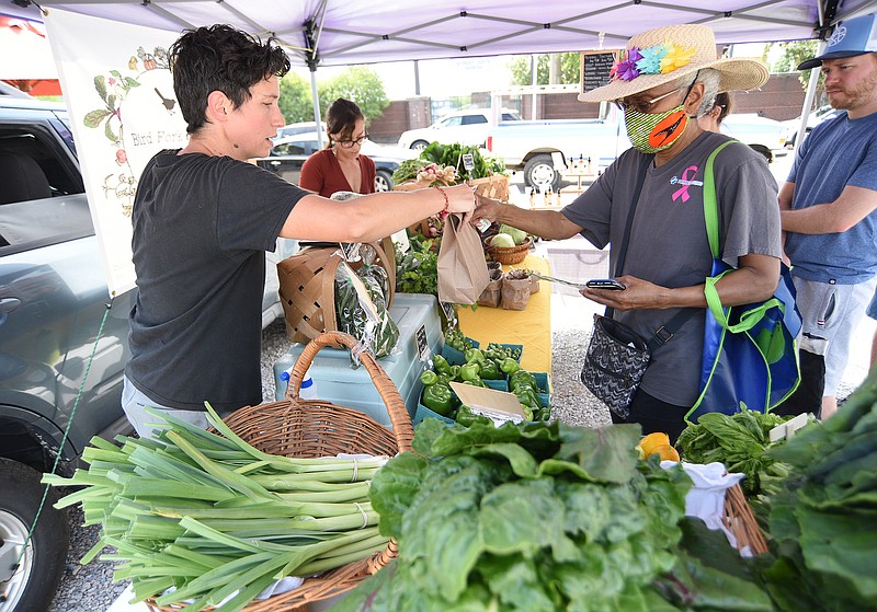 Staff Photo by Matt Hamilton / Stephanie Martin, left, hands a bag of produce to Jean Smith at the Bird Fork Farm booth on Wednesday.