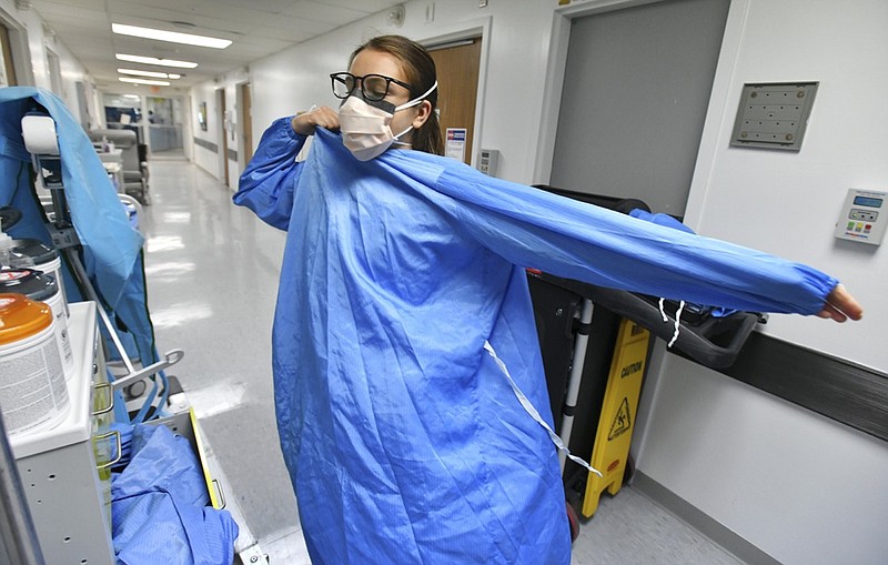 RN Zoe Zinis puts on fresh protective layers before entering the room of an infected patient in the COVID-19 ward at UF Health's downtown in Jacksonville, Fla., campus Friday, July 30, 2021. The second surge of COVID-19 infections in Jacksonville is stretching the capacity of area medical facilities to care for patients. (Bob Self/The Florida Times-Union via AP)