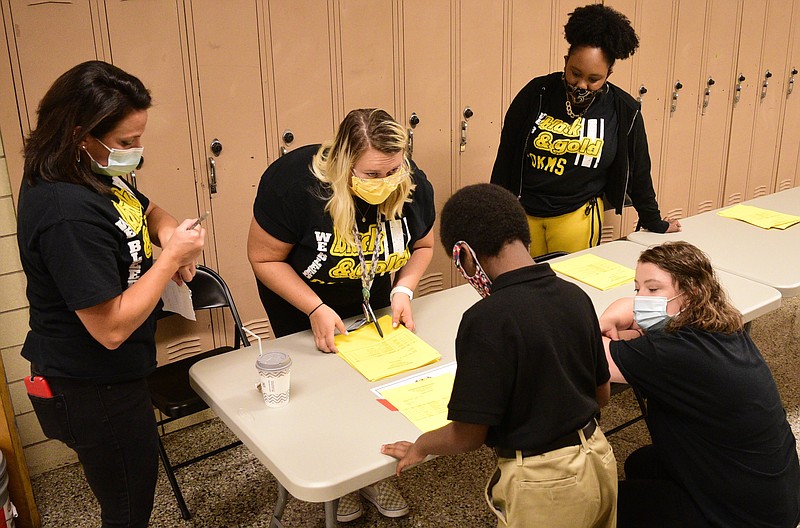 Staff Photo by Robin Rudd / From left, Orchard Knob Middle School teachers, Christina Manton, Brooklyn Caulder, Ayanna Esdaile, and Elaine Dunn comfort a incoming sixth grader, who said he was "scared." Orchard Knob Middle School started the 2021-2022 school year under a Hamilton County Schools system wide mask mandate on August 12, 2021, because of the surge in the Delta variant of the Coronavirus.