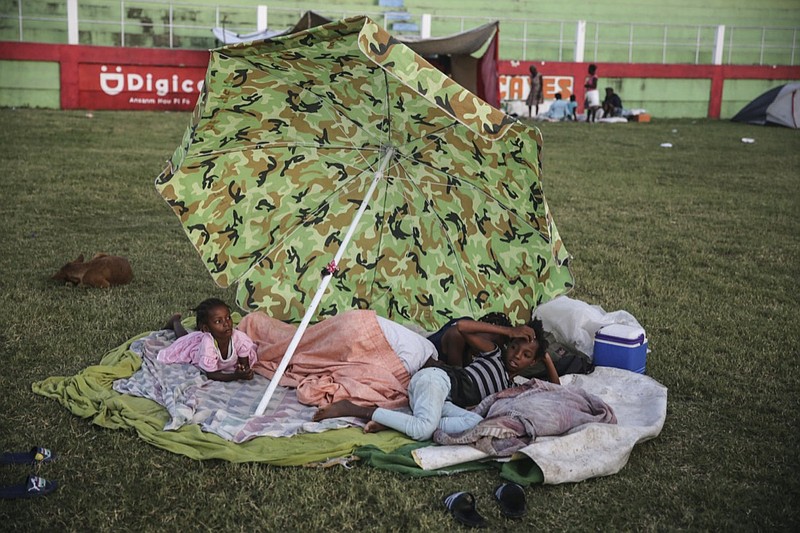 People rest after spending the night at a soccer field following Saturdays 7.2 magnitude earthquake in Les Cayes, Haiti, Sunday, Aug. 15, 2021. (AP Photo/Joseph Odelyn)