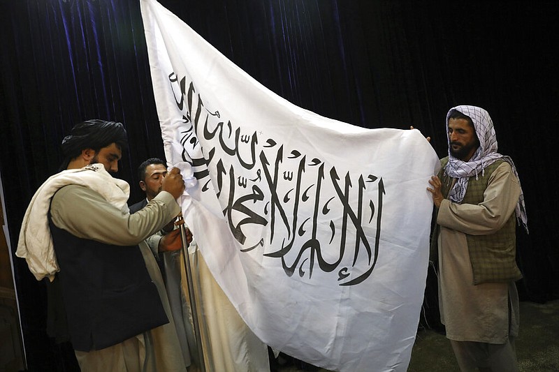 Taliban officials arrange a Taliban flag, before a press conference by Taliban spokesman Zabihullah Mujahid, at the Government Media Information Center, in Kabul, Afghanistan, Tuesday, Aug. 17, 2021. Mujahid vowed Tuesday that the Taliban would respect women's rights, forgive those who resisted them and ensure a secure Afghanistan as part of a publicity blitz aimed at convincing world powers and a fearful population that they have changed. (AP Photo/Rahmat Gul)