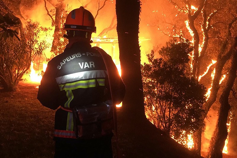 In this photo provided by the fire brigade of the Var region, a fireman battles with a fire near Toulon early Tuesday, Aug. 17, 2021. Hundreds of firefighters on Tuesday battled a fire racing through forests near the French Riviera that forced the evacuation of thousands of people from homes and vacation spots. (SDIS 83 via AP)
