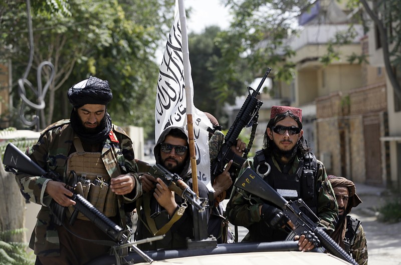 Photo by Rahmat Gul of The Associated Press / In this Aug. 19, 2021, file photo, Taliban fighters display their flag on patrol in Kabul, Afghanistan.