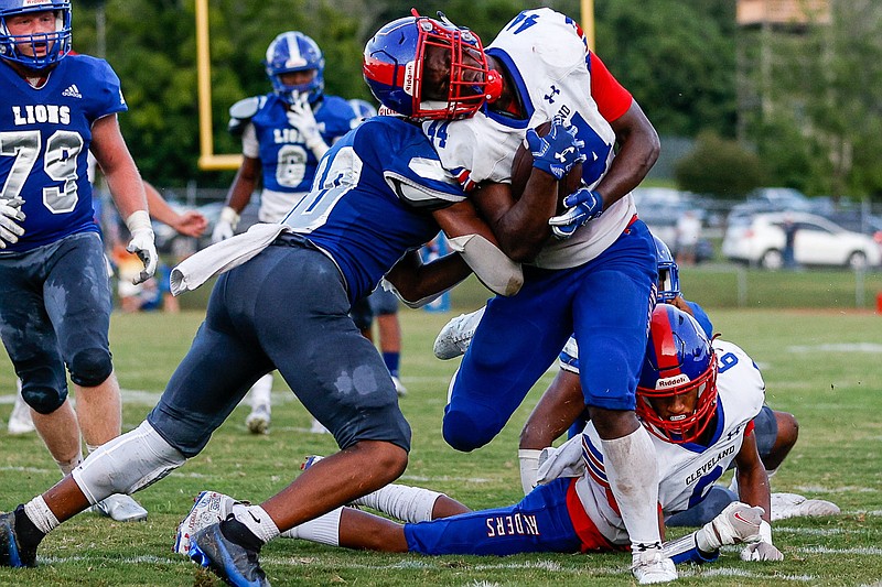 Staff photo by Troy Stolt / Cleveland running back Tetoe Boyd, right, breaks a tackle during Friday night's game at Red Bank. Boyd rushed for 156 yards on 24 carries to help the Blue Raiders beat the Lions 17-10 in the season opener for both teams.