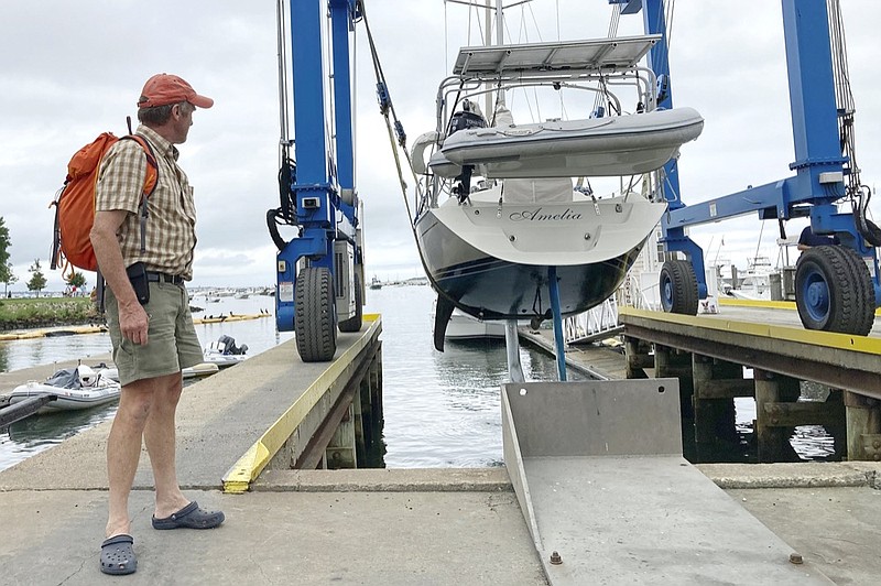 Robin Berthet, of Sheffield, Mass., watches as his sailboat is hauled out of the water onto dry land in advance of an expected storm, Friday Aug. 20, 2021, in Plymouth, Mass. (AP Photo/Phil Marcelo)


