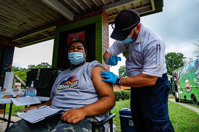 Staff photo by Troy Stolt / Christian Mckibbens is given a COVID-19 vaccine by paramedic Robert Blackburn during a block party put on by Get Vaccinated Chattanooga at the Emma Wheeler Homes on Saturday, Aug. 21, 2021 in Chattanooga, Tenn.