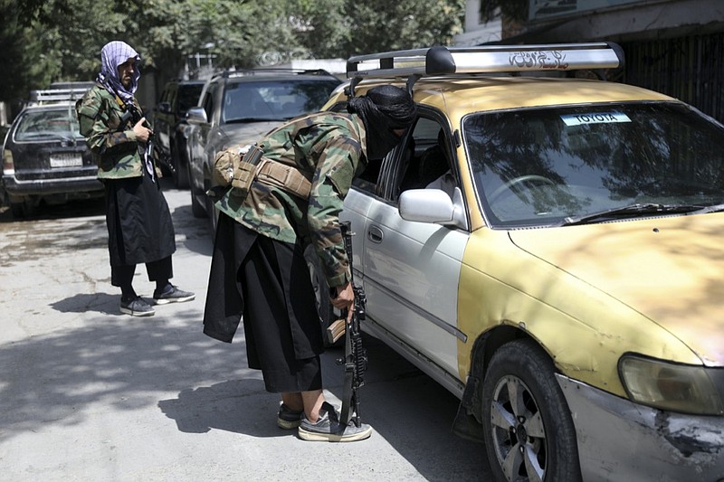 FILE - In this Aug. 22, 2021, file photo, Taliban fighters search a vehicle at a checkpoint on the road in the Wazir Akbar Khan neighborhood in the city of Kabul, Afghanistan. After the Taliban takeover, employees of the collapsed government, civil society activists and women are among the at-risk Afghans who have gone into hiding or are staying off the streets. (AP Photo/Rahmat Gul, File)