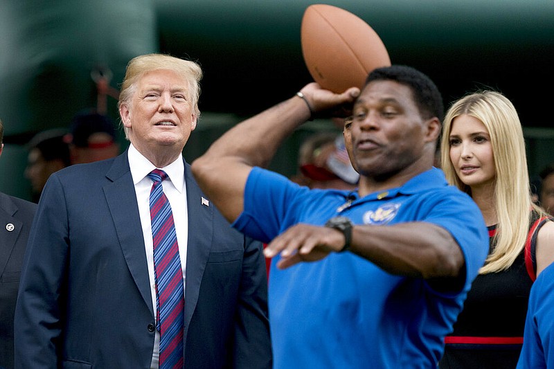 In this May 29, 2018, file photo, President Donald Trump, left, and his daughter Ivanka Trump, right, watch as former football player Herschel Walker, center, throws a football during White House Sports and Fitness Day on the South Lawn of the White House in Washington. On Tuesday, Aug. 17, 2021, Walker filed paperwork to enter the U.S. Senate race in Georgia after months of speculation, joining other Republicans seeking to unseat Democratic Sen. Raphael Warnock in 2022. (AP Photo/Andrew Harnik, File)